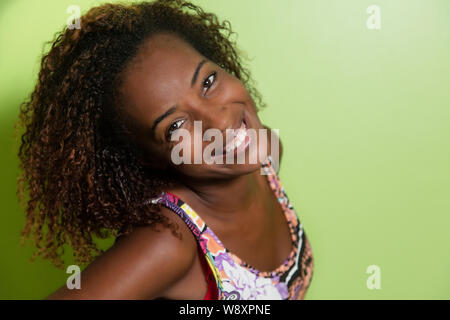 Belle african american woman looking at camera en face d'un mur vert Banque D'Images