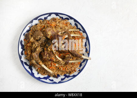 Riz pilaf à l'agneau Côtes , dans un plat traditionnel d'ornements , sur un fond clair . copie espace . Banque D'Images