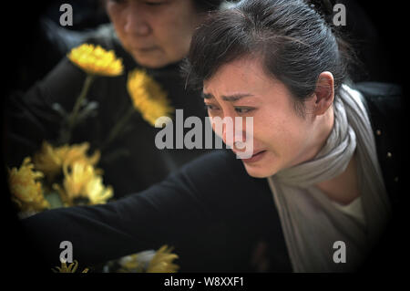 Les gens pleurent comme ils présentent des fleurs pour rendre hommage à leurs proches décédés en face d'un monument portant les noms de donneurs d'organes à un mémorial Banque D'Images