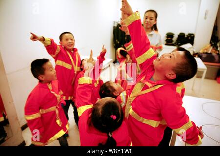 Les jeunes enfants habillés en uniforme de pompier s'amuser dans une aire de professions museum à Pékin, Chine, le 2 octobre 2014. Des médecins et du personnel infirmier aux Banque D'Images