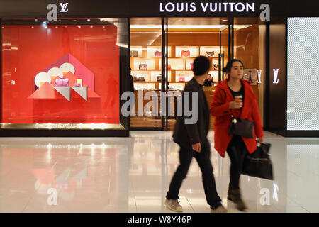 --FILE--Shoppers devant une boutique de mode de Louis Vuitton (LV) à Fuzhou City, dans le sud-est de la province de Fujian, Chine 17 mars 2014. LVMH Moet Hennessy Banque D'Images