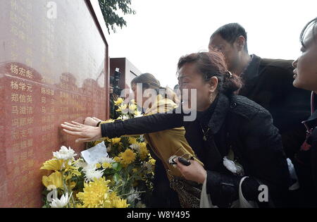 Les gens pleurent comme ils présentent des fleurs pour rendre hommage à leurs proches décédés en face d'un monument portant les noms de donneurs d'organes à un mémorial Banque D'Images