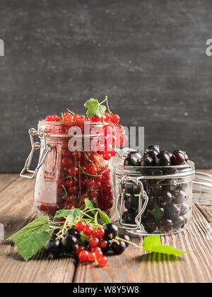 Frais mûrs de cassis rouge berry dans divers pots de verre sur un fond sombre. Selective focus.cadre vertical Banque D'Images