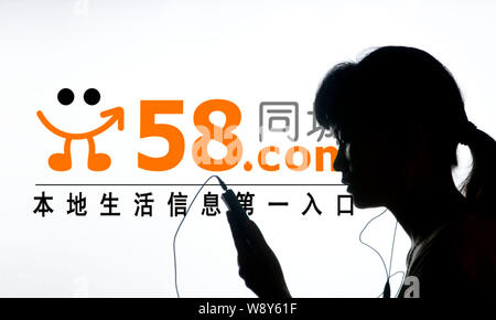 --FILE--Une femme chinoise utilise son téléphone portable en face d'une publicité en ligne pour 58.Com site classé de Shaoyang, Hunan Chines centrale pr Banque D'Images