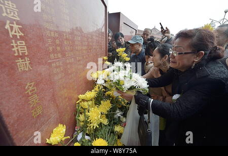 Les gens pleurent comme ils présentent des fleurs pour rendre hommage à leurs proches décédés en face d'un monument portant les noms de donneurs d'organes à un mémorial Banque D'Images