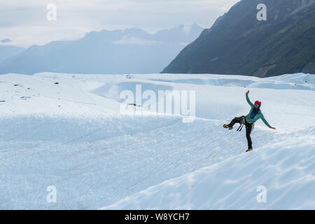 Guide ludique glacier femme debout sur une jambe sur le Glacier Matanuska en Alaska Banque D'Images