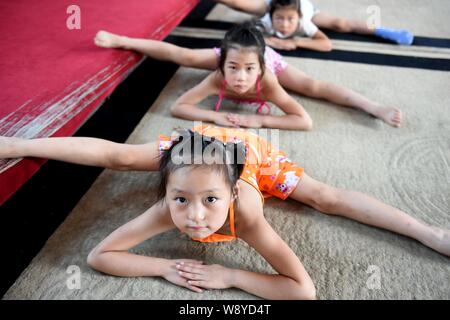 Les jeunes filles chinoises plier leur corps et ne les sépare sur le sol pour pratiquer la gymnastique à un centre de formation de gymnastique à Bozhou ville, est de la Chine Banque D'Images