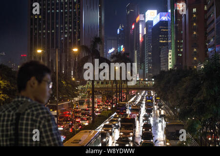 --FILE--Un homme montres de masses des véhicules se déplaçant à slowy dans un embouteillage aux heures de pointe dans la région de Wan Chai, Hong Kong, Chine, 20 août 2014. Alors que les manifestations i Banque D'Images