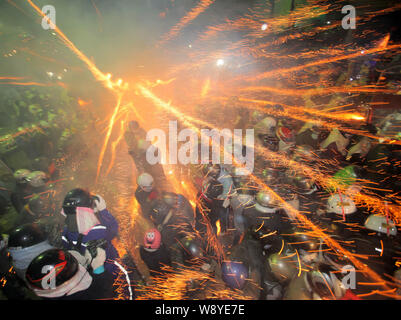 --FILE--visiteurs portant des casques rester près de l'explosion de fusées bouteille d'obtenir pulvérisé par le feu d'étincelles pendant le Festival des fusées Yanshui Beehive Banque D'Images