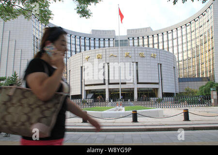 --FILE--un piéton parle sur son téléphone portable alors qu'elle passe devant le siège et siège social de la Banque populaire de Chine (PBOC), China's centra Banque D'Images