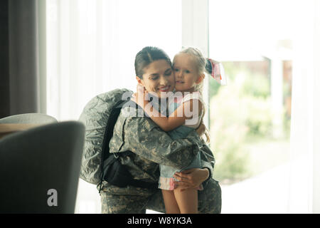 Sac à dos militaire woman hugging her lovely girl Banque D'Images