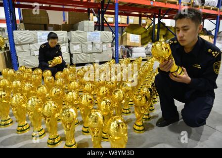 Les agents des douanes chinoises vérifier fake World Cup trophées qu'ils ont saisi dans un entrepôt dans la ville de Yiwu, province de Zhejiang, Chine de l'est le 16 avril 2014. Plus de t Banque D'Images