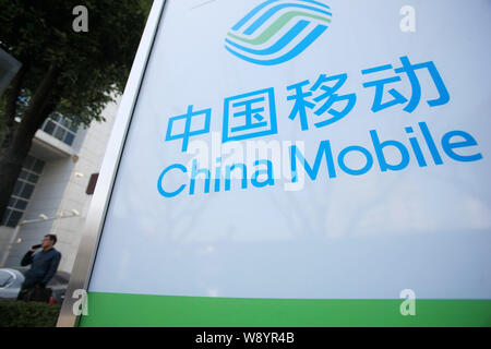 --FILE--un piéton parle sur son téléphone portable à côté d'une publicité pour China Mobile à Shanghai, Chine, 13 mars 2014. China Mobile Ltd., le w Banque D'Images