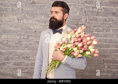 Cadeau romantique. Macho prêt date romantique. Tulipes pour elle. L'homme grand Bow-tie tuxedo tenir fleurs bouquet. De cœur sincère. Choses qui font l'homme gentleman. Homme romantique avec des fleurs. Banque D'Images