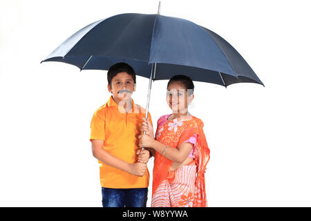 Les enfants prétendant être un couple debout sous un parapluie Banque D'Images