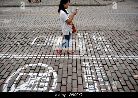 Un piéton utilise son portable qu'elle marche sur le trottoir de téléphone mobile à Chongqing, Chine, le 13 septembre 2014. À gauche, les gens se concentrer sur Banque D'Images