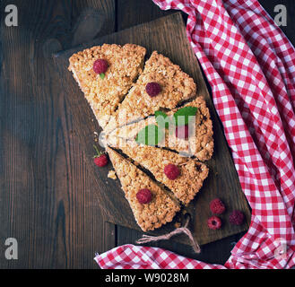 Fabricants de pièces triangulaires de tarte crumble aux pommes sur une planche de bois brun, vue du dessus Banque D'Images