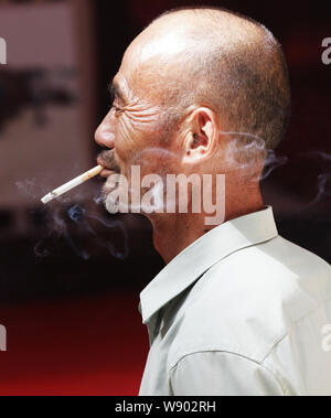 --FILE--un Chinois fume sur une route dans la ville de Yichang, province de Hubei, Chine centrale 15 septembre 2013. Le chef de l'Organisation mondiale de la Santé Banque D'Images