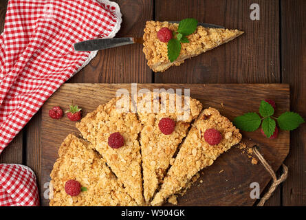 Fabricants de pièces triangulaires de tarte crumble aux pommes sur une planche de bois brun, vue du dessus Banque D'Images