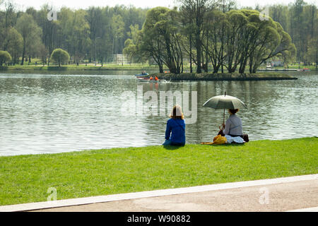 01-05-2018, Russie, Moscou, le parc Tsaritsyno Manor, vacances mai dans le parc, les femmes se trouvent sur le lac sur une pelouse verte. Une fille avec siège parapluie Banque D'Images