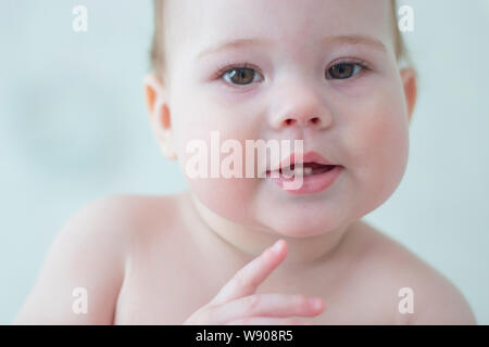 Petit bébé garçon fille enfant 7-8 mois montre les deux premières dents, portrait visage du bébé de près. La dentition les dents de lait de bébé petit enfant portrait dans Banque D'Images