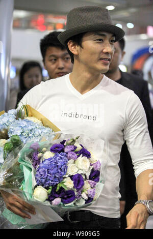 L'acteur sud-coréen Song Seung-heon détient des bouquets de fleurs pendant qu'il marche sur le terminal de l'aéroport international Beijing Capital après son arrivée je Banque D'Images