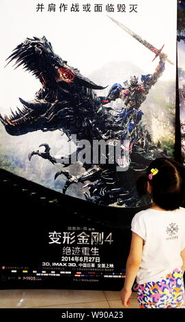 Une petite fille regarde une affiche de film de Hollywood, Transformers : l'âge d'extinction, dans un cinéma du centre-ville de Yichang, province de Hubei, Chine 2 Juil Banque D'Images