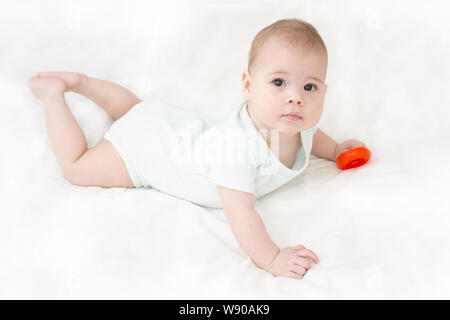 Fille Garçon bébé est posé sur son estomac en blanc. European caucasien enfant avec les yeux bruns, vue de dessus à la recherche de l'appareil photo. Portrait of baby Banque D'Images