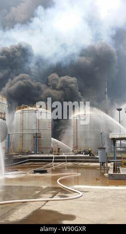 Les pompiers chinois eau flexible pour éteindre l'incendie après une explosion dans une raffinerie de pétrole de Sinopec Yangzi Petrochemical Company à Nanjing, ville Banque D'Images