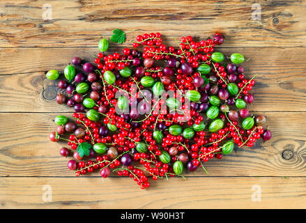 Vue descendante de feuilles vertes et rouges fraîchement récolté les fruits de cassis, de groseille rouge et verte sur la table en bois. Fond d'aliments biologiques. Banque D'Images