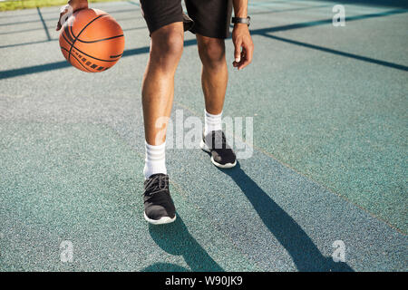 Jambes musclées de joueur de basket-ball méconnaissable dans la formation de la cour extérieure, copy space Banque D'Images