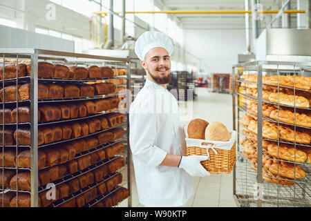 Sourires baker barbu tenant un panier de pain au fournil Banque D'Images