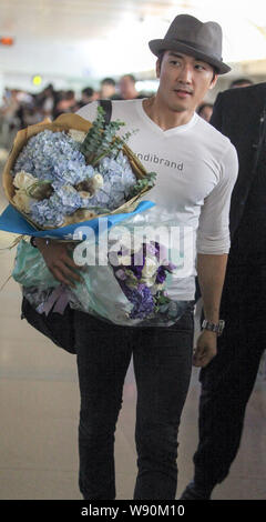 L'acteur sud-coréen Song Seung-heon détient des bouquets de fleurs pendant qu'il marche sur le terminal de l'aéroport international Beijing Capital après son arrivée je Banque D'Images