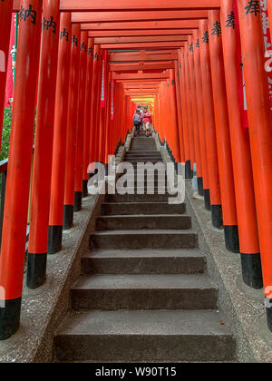 People walking down steps dans un tunnel de Torii en bois rouge de portes à la hie Jinja, Nagatacho, Tokyo Banque D'Images