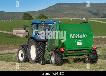 Faire de l'ensilage préfané récolte sur une colline, la ferme avec un New Holland T6030 et un McHale 5500 balles. , Cumbria (Royaume-Uni). Banque D'Images
