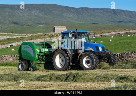 Faire de l'ensilage préfané récolte sur une colline, la ferme avec un New Holland T6030 et un McHale 5500 balles. , Cumbria (Royaume-Uni). Banque D'Images