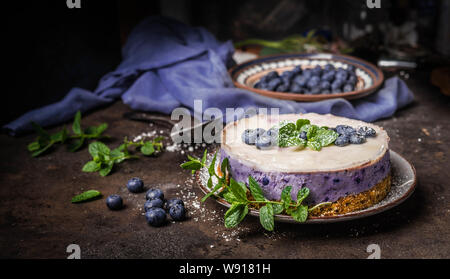 Vegan gâteau aux bleuets sur fond foncé table de cuisine rustique avec les baies fraîches, vue de côté. L'alimentation saine Banque D'Images