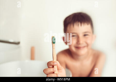 L'enfant brosses les dents avec une brosse à dents en bambou. Banque D'Images