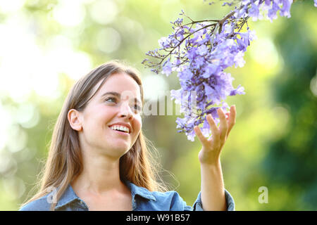 Happy woman enjoying nature fleurs toucher debout dans un parc Banque D'Images