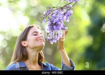 Franchise woman smelling flowers standing in a park Banque D'Images