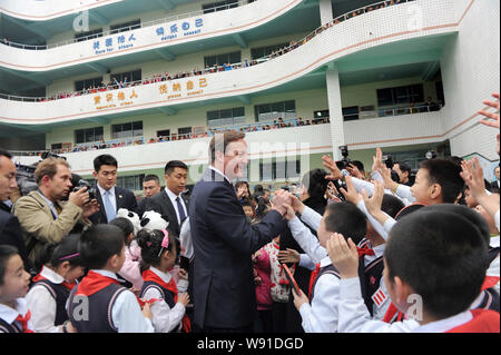 Le Premier ministre britannique, David Cameron, centre, est accueilli par de jeunes étudiants chinois lors de sa visite à l'école primaire de la ville de Chengdu, dans le sud-ouest de Ch Banque D'Images