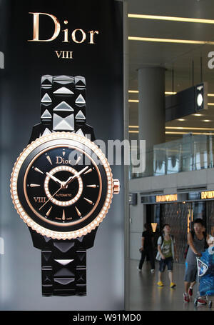 --FILE--passagers chinois passent devant une publicité pour Dior montres à l'Aéroport International de Pudong à Shanghai, Chine, le 13 juillet 2013. Les prix Banque D'Images