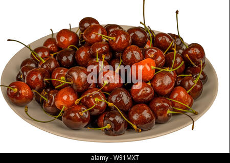 Les cerises dans un plat sur la table. Isoler sur fond blanc Banque D'Images