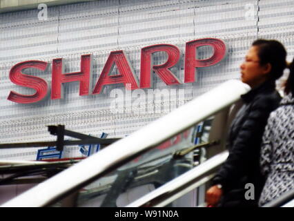 --FILE--piétons devant une de Sharp à Shanghai, Chine, le 26 février 2013. Japans Sharp Corp., un des principaux fournisseurs d'écrans à Apple Banque D'Images