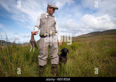 Le gardien chef Mark Palmer, avec le chien de paddy, les états d'une partie de tir sur les maures à l'Estate dans Glen Clova Rottal, près de Kirriemuir, Angus, sur le glorieux douzième, le début de la saison de tir des tétras. Banque D'Images