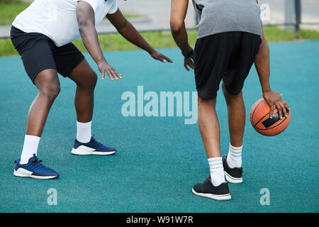 Vue arrière de l'angle faible de deux gars afro-américain jouant au basket-ball en plein air, copy space Banque D'Images