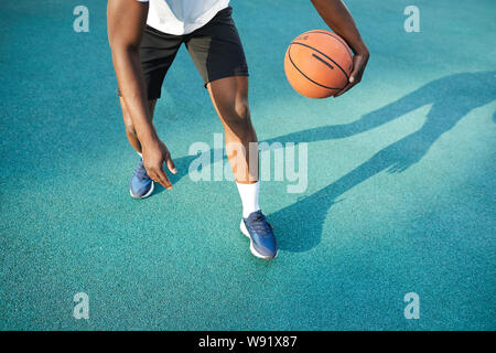 La section basse photo d'action de l'homme africain méconnaissable jouant au basket-ball en plein air, copy space Banque D'Images