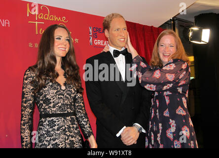 Un invité, droite, pose en compagnie de personnages de cire du Prince William, duc de Cambridge, et de la princesse Kate Middleton, duchesse de Cambridge, lors d'une exposition marki Banque D'Images