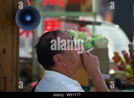 --FILE--un Chinois fume une cigarette sur une route à Qingdao, Chine de l'est la province de Shandong, le 30 mai 2013. Chines efforts anti-tabac dans le passé d Banque D'Images