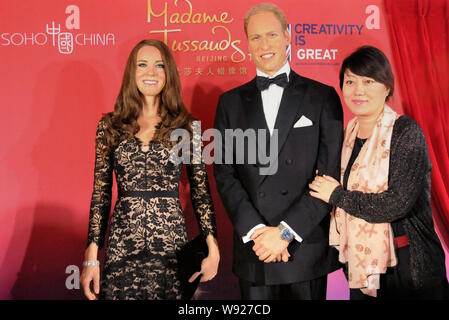 Un invité, droite, pose en compagnie de personnages de cire du Prince William, duc de Cambridge, et de la princesse Kate Middleton, duchesse de Cambridge, lors d'une exposition marki Banque D'Images